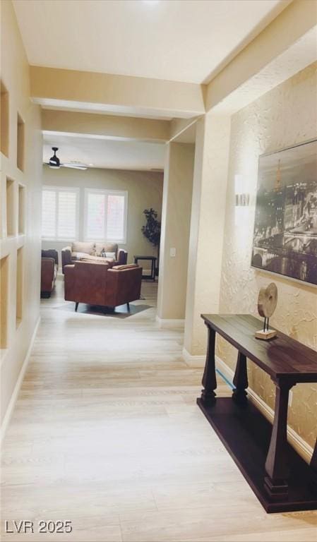 hallway with wood finished floors, baseboards, and a textured wall