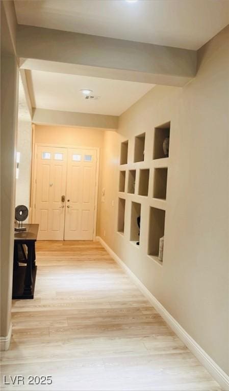 corridor featuring light wood-style flooring and baseboards