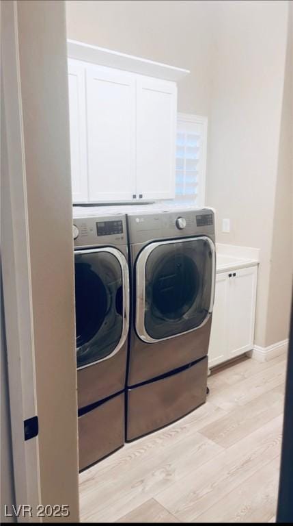 laundry area featuring washing machine and clothes dryer, cabinet space, light wood-style floors, and baseboards