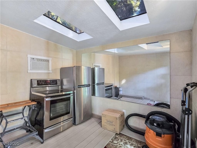 5159 N Monte Cristo Way, Las Vegas, NV 89149 - kitchen with stainless steel appliances, tile walls, a skylight, wood finished floors, and a textured ceiling