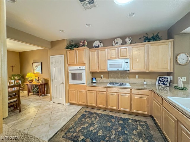 kitchen featuring white appliances, light brown cabinetry, light countertops, and recessed lighting