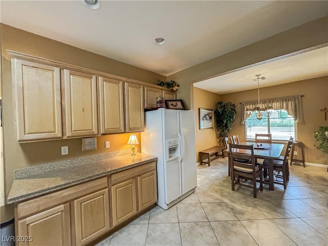 kitchen featuring white fridge with ice dispenser, a chandelier, light tile patterned floors, pendant lighting, and baseboards