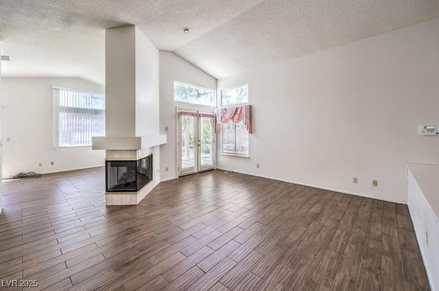 2753 Port Of Call Dr, Las Vegas, NV 89128 - unfurnished living room featuring lofted ceiling, a textured ceiling, dark wood-style flooring, a tile fireplace, and baseboards