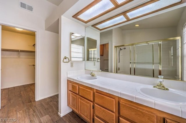 2753 Port Of Call Dr, Las Vegas, NV 89128 - bathroom with a shower stall, double vanity, wood finished floors, and a spacious closet