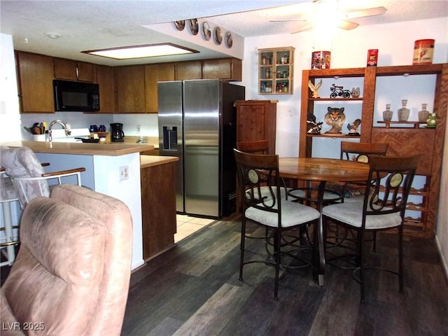3720 Desert Marina Dr Unit 33, Laughlin, NV 89029 - kitchen featuring stainless steel refrigerator with ice dispenser, black microwave, wood finished floors, a peninsula, and ceiling fan
