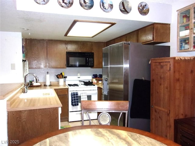 3720 Desert Marina Dr Unit 33, Laughlin, NV 89029 - kitchen featuring black microwave, white range with gas stovetop, a sink, light countertops, and freestanding refrigerator