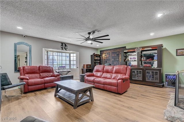 living area featuring wood finished floors, recessed lighting, ceiling fan, a textured ceiling, and baseboards