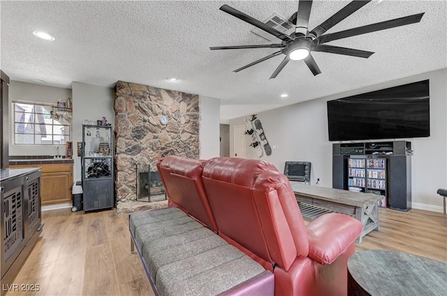living area featuring a textured ceiling, light wood-style flooring, ceiling fan, and recessed lighting