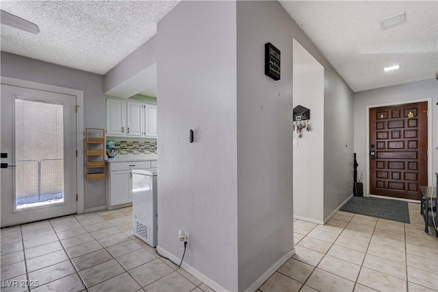 entrance foyer with a textured ceiling, light tile patterned floors, and baseboards