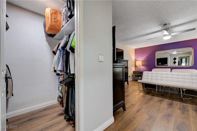 bedroom with a textured ceiling, wood finished floors, baseboards, and a ceiling fan