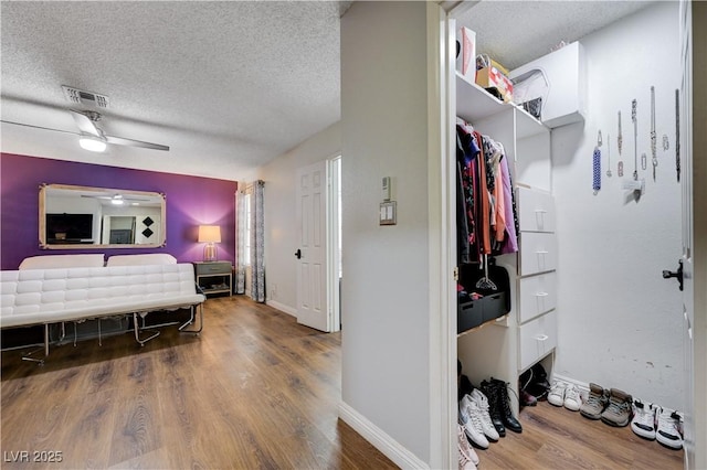 bedroom with a textured ceiling, wood finished floors, baseboards, and a ceiling fan