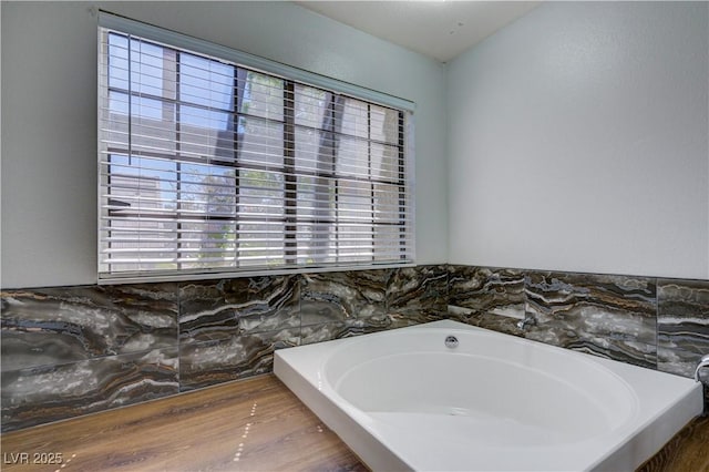 full bathroom with a bath and wood finished floors