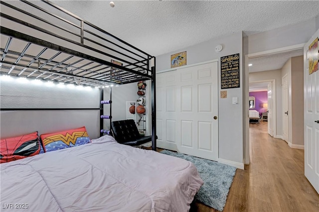 bedroom featuring wood finished floors, baseboards, a textured ceiling, and a closet