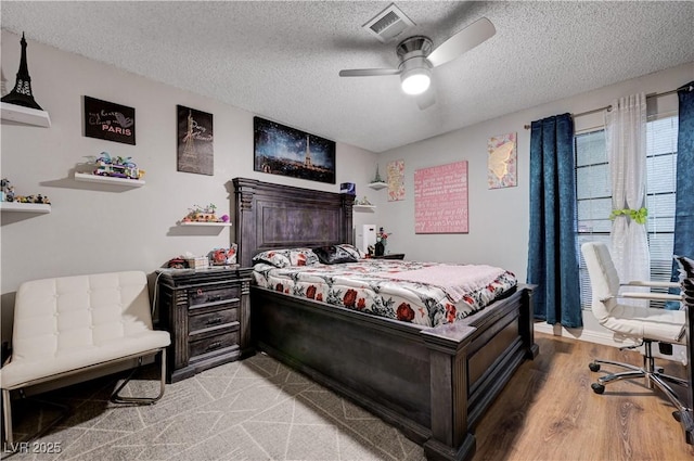 bedroom with a textured ceiling, light wood-style floors, and a ceiling fan