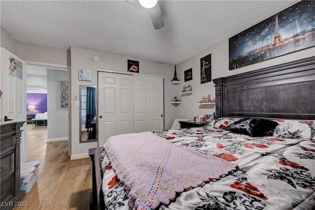 bedroom featuring light wood-type flooring, a closet, a textured ceiling, a ceiling fan, and baseboards
