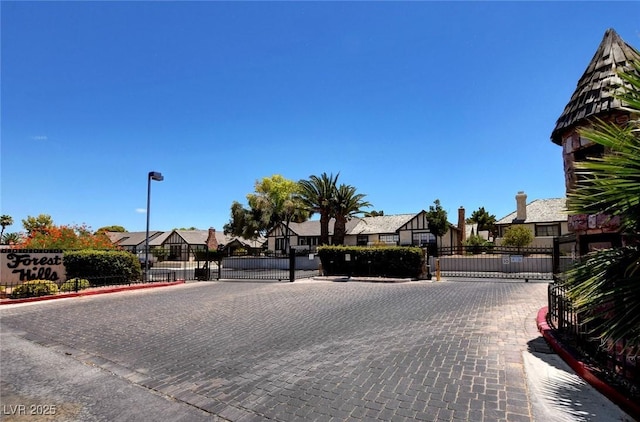 view of road with a residential view, a gate, curbs, and street lights