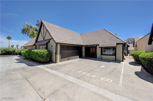 view of front facade with stucco siding, a tiled roof, and uncovered parking