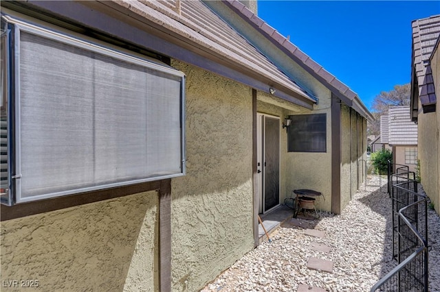 view of side of home featuring stucco siding and fence