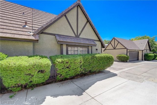 view of property exterior featuring an attached garage, stucco siding, driveway, and a tiled roof