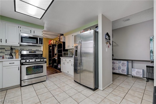 kitchen with stainless steel appliances, white cabinetry, light tile patterned floors, and light countertops