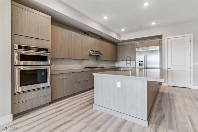 9125 Las Manaitas Ave Unit 302, Las Vegas, NV 89144 - kitchen with appliances with stainless steel finishes, a sink, under cabinet range hood, light wood-style flooring, and recessed lighting