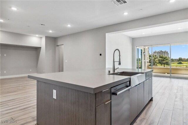 9125 Las Manaitas Ave Unit 302, Las Vegas, NV 89144 - kitchen with stainless steel dishwasher, a sink, light wood finished floors, open floor plan, and an island with sink