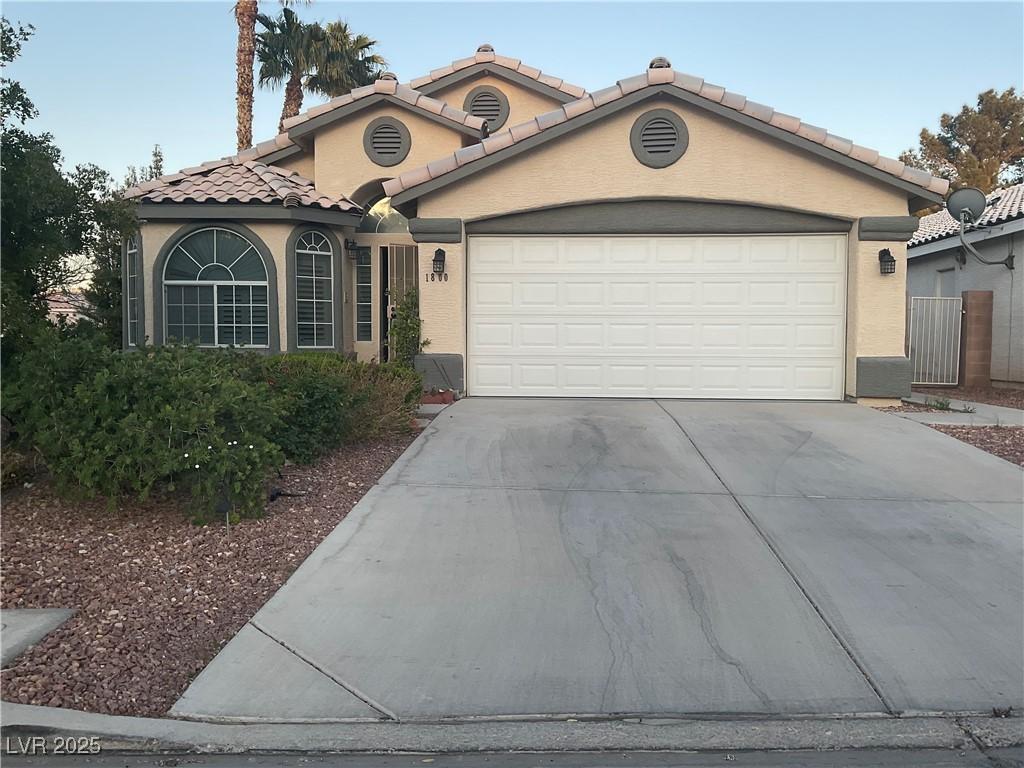 1800 Quail Point Ct, Las Vegas, NV 89117 - mediterranean / spanish-style home with concrete driveway, a garage, a tiled roof, and stucco siding