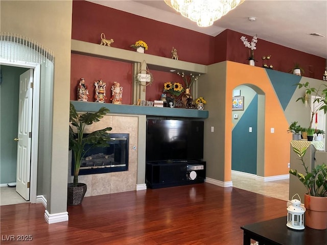 1800 Quail Point Ct, Las Vegas, NV 89117 - living room with wood finished floors, arched walkways, a chandelier, a tiled fireplace, and baseboards