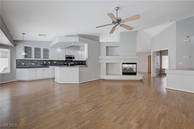 472 Staghorn Pass Ave, Las Vegas, NV 89183 - unfurnished living room with light wood-style floors, a ceiling fan, baseboards, high vaulted ceiling, and a fireplace