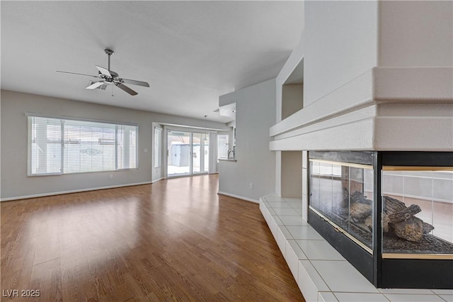 472 Staghorn Pass Ave, Las Vegas, NV 89183 - unfurnished living room with wood finished floors, a ceiling fan, a tiled fireplace, and baseboards