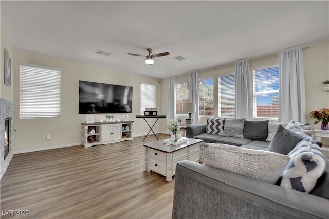 3217 Bonassola Ave, North Las Vegas, NV 89031 - living area featuring light wood-type flooring, baseboards, a ceiling fan, and a glass covered fireplace