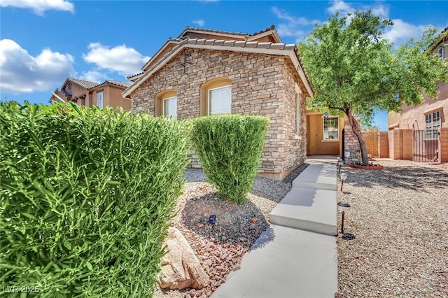 3217 Bonassola Ave, North Las Vegas, NV 89031 - view of front of property featuring stone siding, a tiled roof, fence, and stucco siding