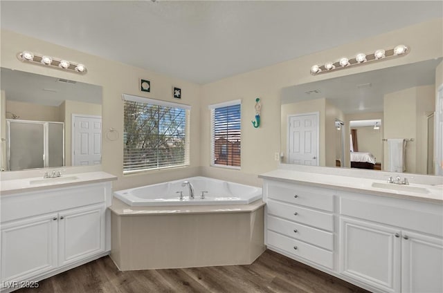 3217 Bonassola Ave, North Las Vegas, NV 89031 - ensuite bathroom featuring a stall shower, two vanities, wood finished floors, and a bath