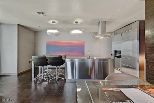 4381 W Flamingo Rd Unit 1101, Las Vegas, NV 89103 - kitchen featuring wood finished floors, stainless steel microwave, island range hood, baseboards, and white cabinets