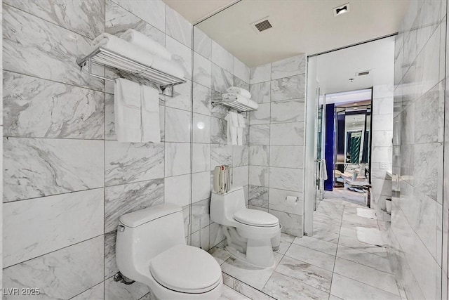 4381 W Flamingo Rd Unit 1101, Las Vegas, NV 89103 - bathroom featuring toilet, tile walls, and marble look tiles