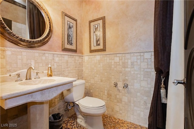 7625 Coley Ave, Las Vegas, NV 89117 - half bath with toilet, a sink, wainscoting, tile walls, and tile patterned flooring