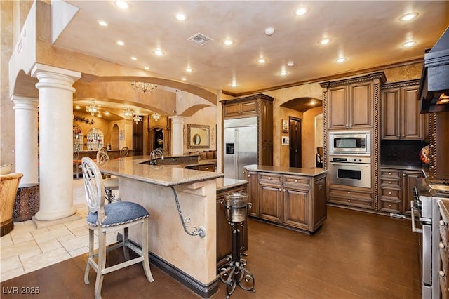 7625 Coley Ave, Las Vegas, NV 89117 - kitchen featuring arched walkways, built in appliances, a large island, ornate columns, and recessed lighting