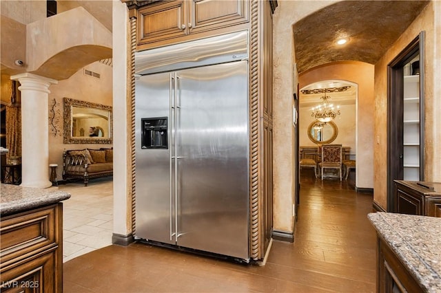 7625 Coley Ave, Las Vegas, NV 89117 - kitchen with stainless steel built in fridge, arched walkways, ornate columns, a chandelier, and light stone counters