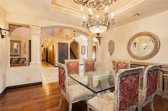 7625 Coley Ave, Las Vegas, NV 89117 - dining space with arched walkways, ornate columns, a chandelier, a raised ceiling, and wood-type flooring