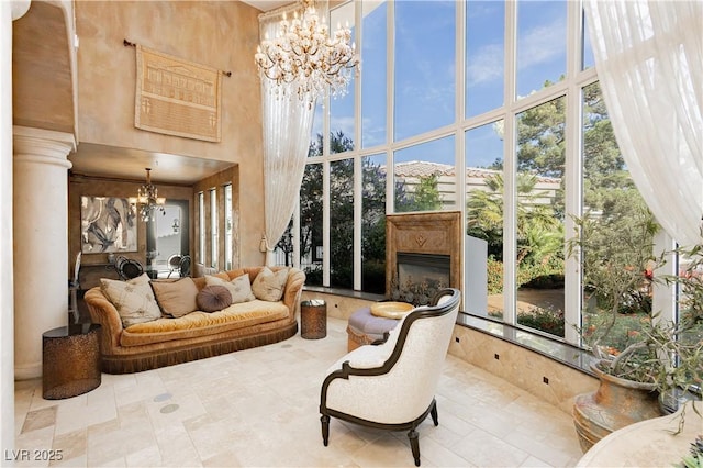 7625 Coley Ave, Las Vegas, NV 89117 - living room with a chandelier, a high ceiling, a glass covered fireplace, and tile patterned flooring