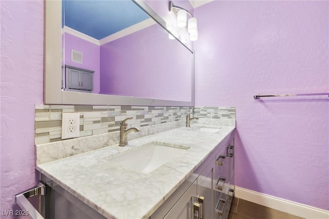 6655 Flaminian Ln Unit 104, North Las Vegas, NV 89084 - bathroom featuring crown molding, baseboards, double vanity, tasteful backsplash, and a textured wall