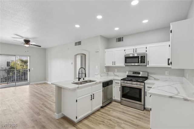 2201 Ramsgate Dr Unit 327, Henderson, NV 89074 - kitchen with stainless steel appliances, a sink, a peninsula, arched walkways, and light stone counters