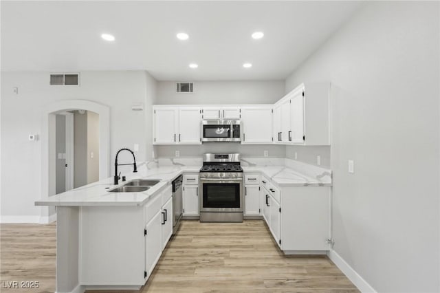 2201 Ramsgate Dr Unit 327, Henderson, NV 89074 - kitchen with appliances with stainless steel finishes, a sink, a peninsula, light wood-style flooring, and arched walkways
