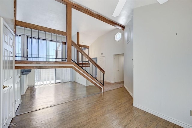 532 Greenbriar Pl, Boulder City, NV 89005 - unfurnished living room featuring wood finished floors, stairway, baseboards, beam ceiling, and high vaulted ceiling