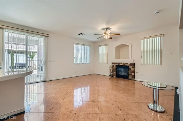 89 Autumn Day St, Henderson, NV 89012 - unfurnished living room featuring plenty of natural light, ceiling fan, a stone fireplace, and tile patterned flooring