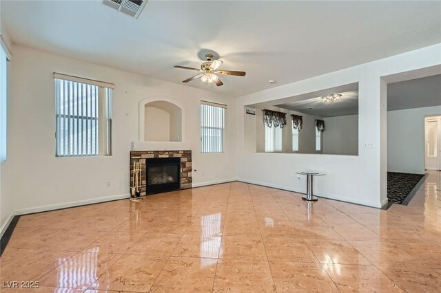 89 Autumn Day St, Henderson, NV 89012 - unfurnished living room featuring ceiling fan, baseboards, and a stone fireplace