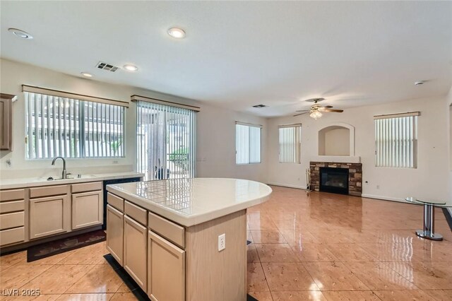 89 Autumn Day St, Henderson, NV 89012 - kitchen with a sink, a stone fireplace, a ceiling fan, a center island, and light tile patterned floors