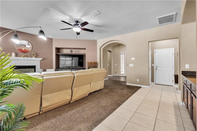9362 Wilderness Glen Ave, Las Vegas, NV 89178 - living room featuring arched walkways, ceiling fan, light tile patterned floors, a tile fireplace, and baseboards