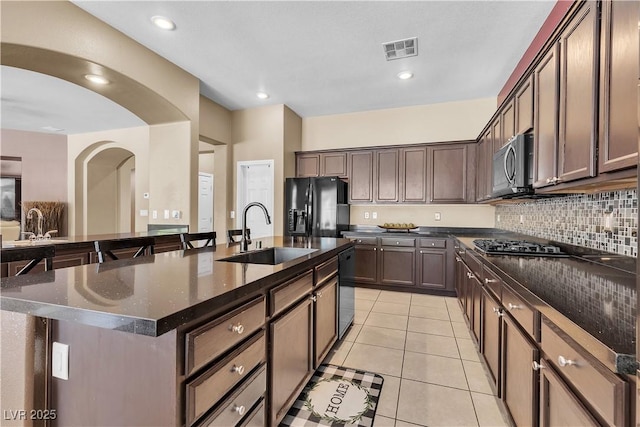 9362 Wilderness Glen Ave, Las Vegas, NV 89178 - kitchen featuring black fridge with ice dispenser, a sink, stainless steel microwave, decorative backsplash, and light tile patterned floors