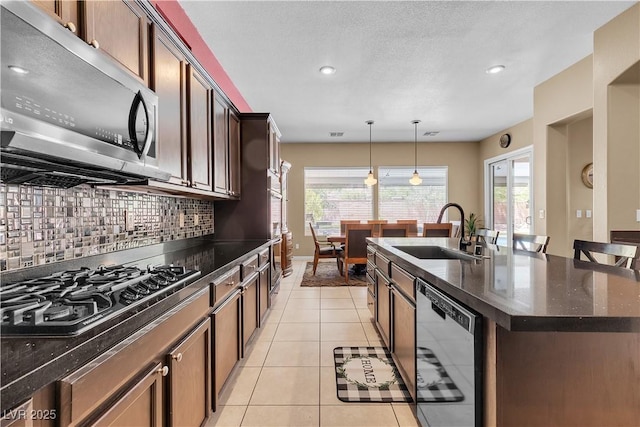 9362 Wilderness Glen Ave, Las Vegas, NV 89178 - kitchen with stainless steel microwave, dishwashing machine, a sink, an island with sink, and gas cooktop